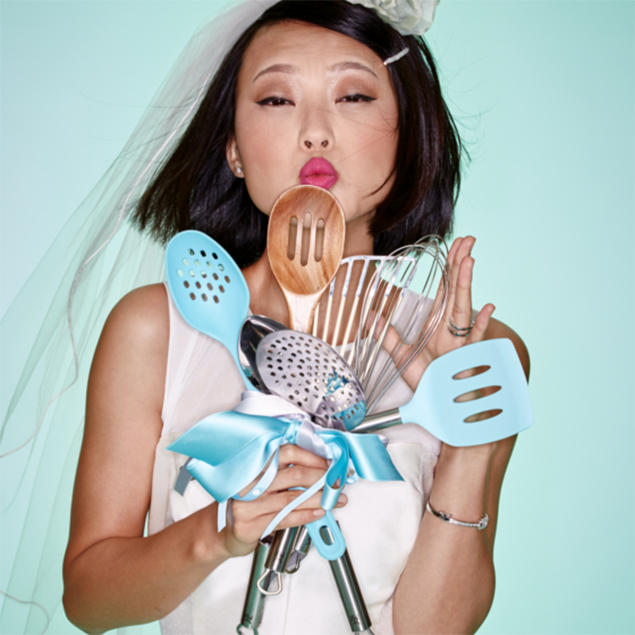 Bride posing with a bouquet of cooking utensils.